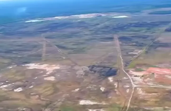 Vista aérea do terreno da refinaria, com estradas de terra que se cruzam e trechos de terra vermelha