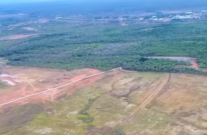 Vista aérea do terreno da refinaria, com uma estrada de terra ao lado da mata